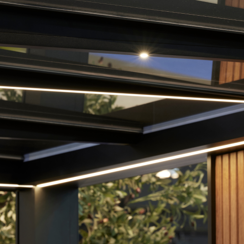 Binnenopname van de Calista terrasoverkapping 's avonds met geïntegreerde LED-spots en ledstrip in het plat dak