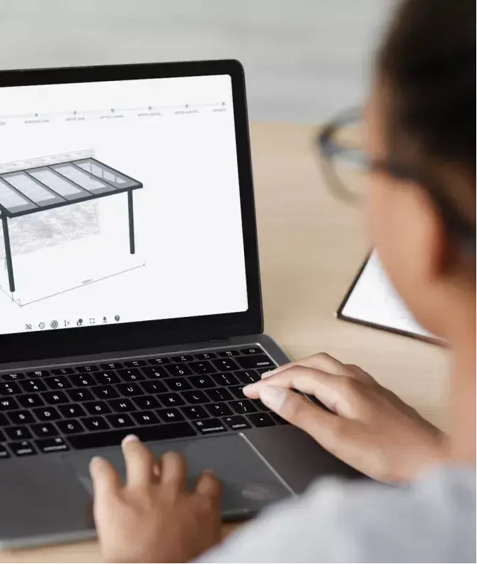 Person designing a modern veranda with a dark frame and glass roof using a laptop configurator.